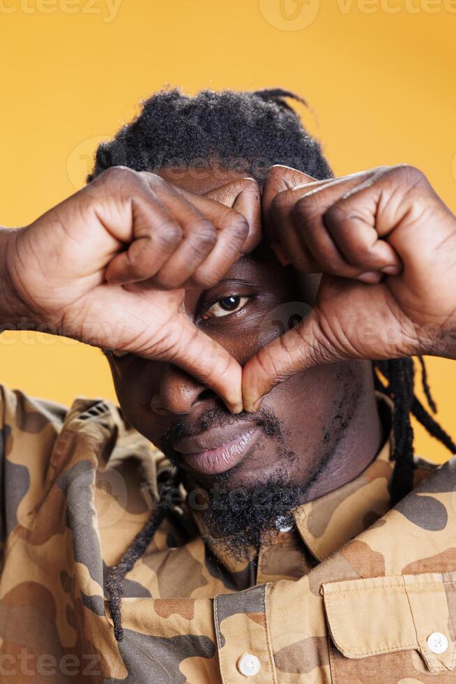 Excited positive man making valentine s day gesture, doing heart shape with hands in studio over yellow background. African american person showing affection and emotion, doing love sign photo