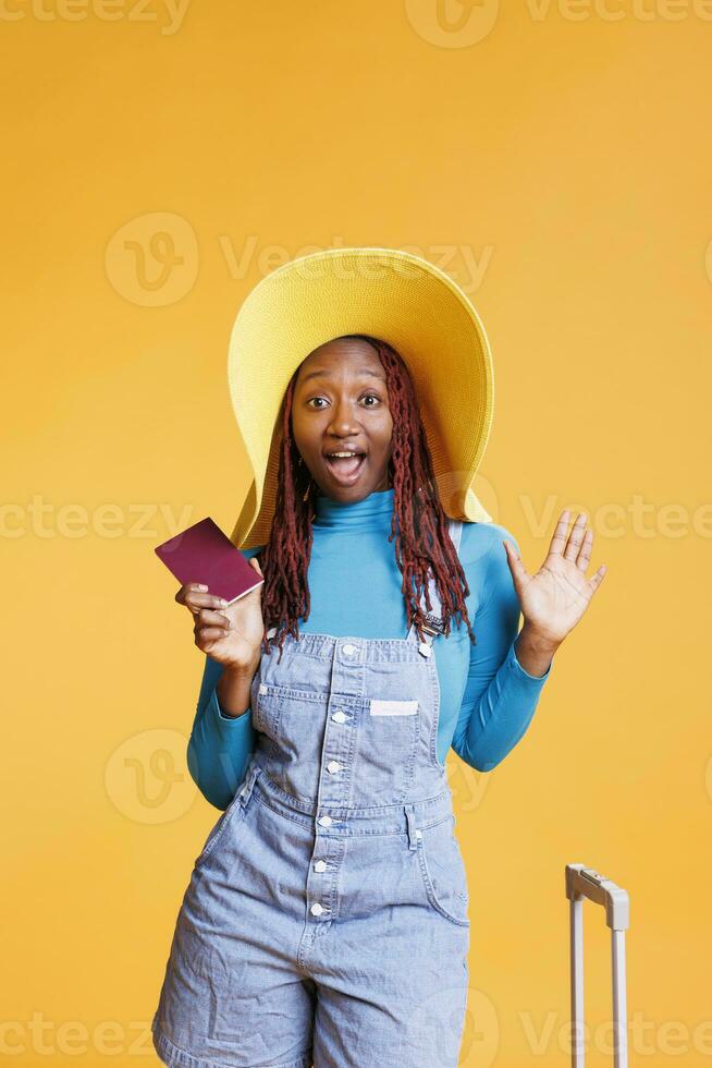 Young adult being happy about journey, using passport to travel on international destination getaway. Female model travelling on new vacation adventure with suitcase and luggage. photo