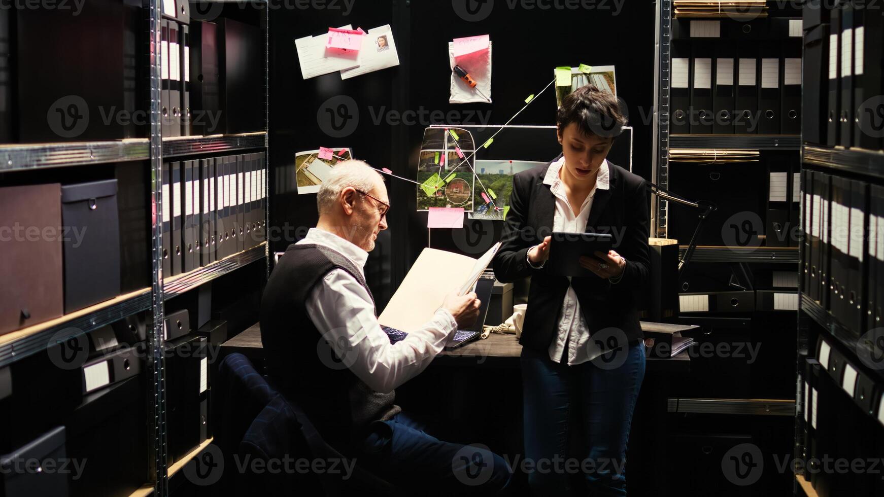 Experts team review evidence reports together with classified documents, gathering intelligence and incriminating proof. Inspector and agent taking notes to for private investigation. photo