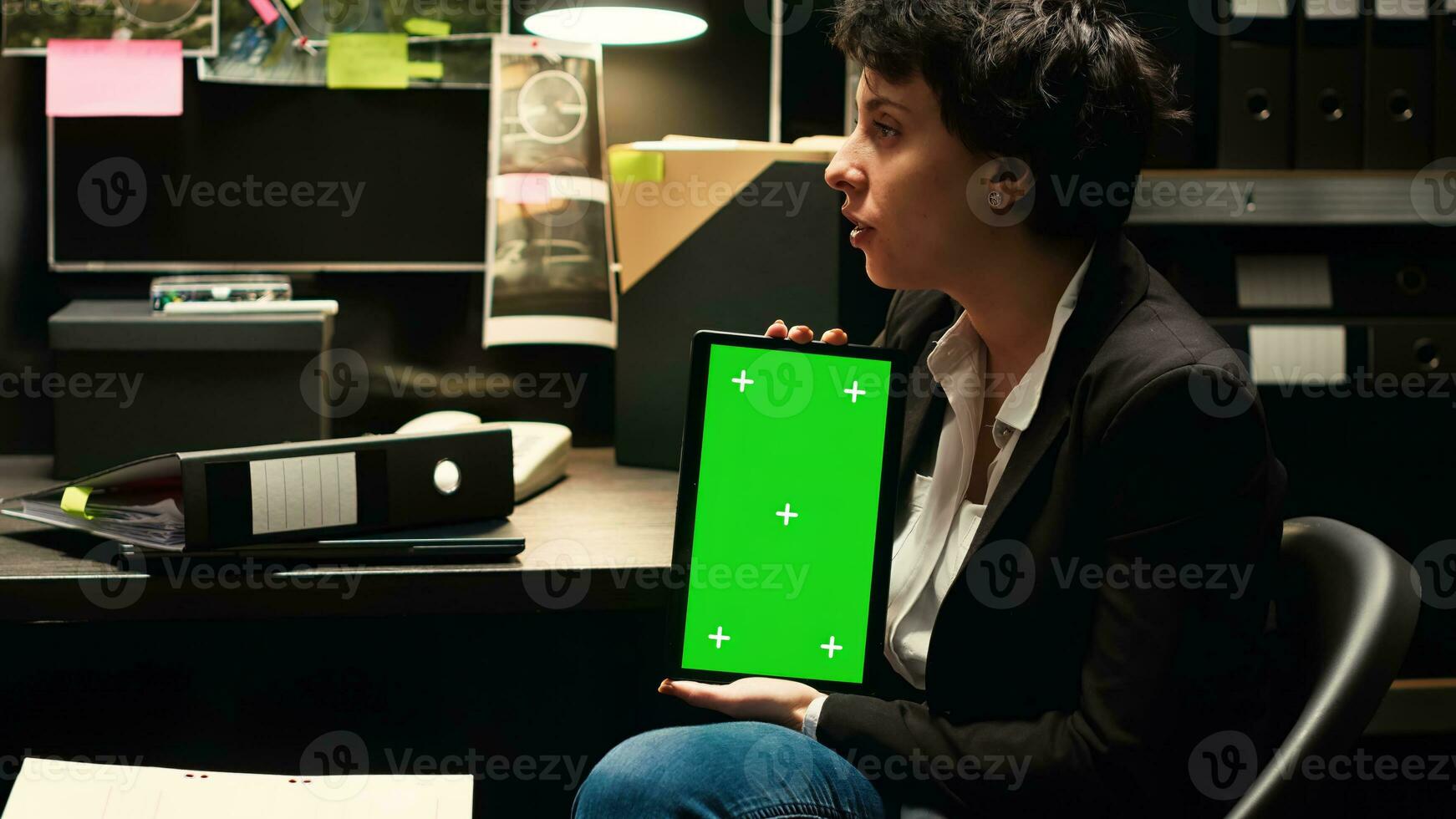 Law agent holds tablet with greenscreen to review classified records and solve mistery. Inspectors team conducting criminal investigation with mockup and isolated chromakey display. photo