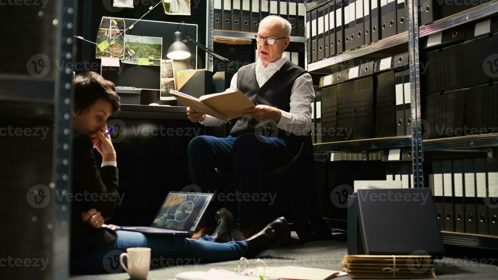 Law officers review case files in incident room, reading confidential documents to piece puzzle together and solve crime. Team of private detectives undertaking investigation, secret mission. photo