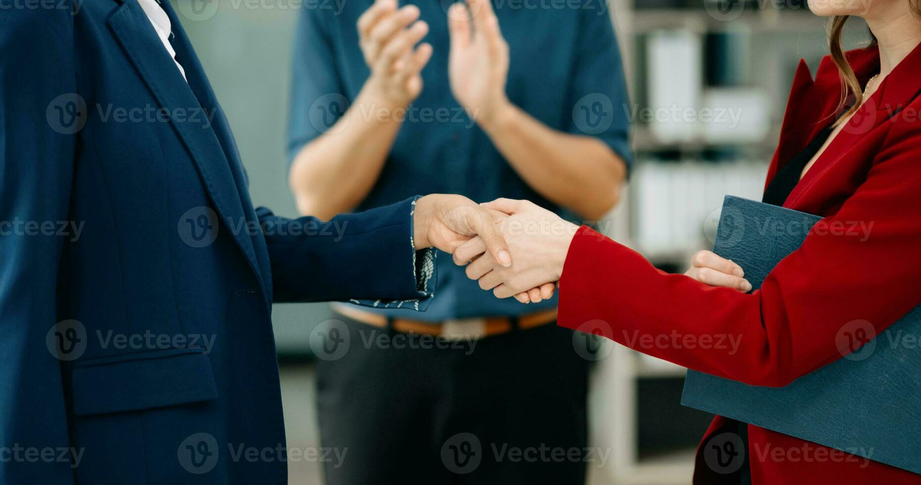 Business people shaking hands during a meeting. Two happy young businessmen and woman photo