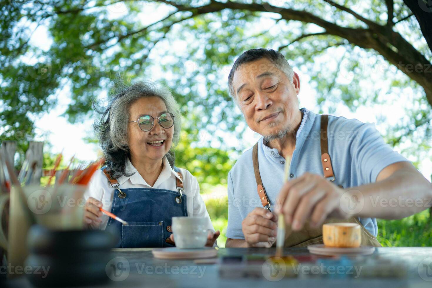 In the pottery workshop, an Asian retired couple is engaged in pottery making and clay painting activities. photo