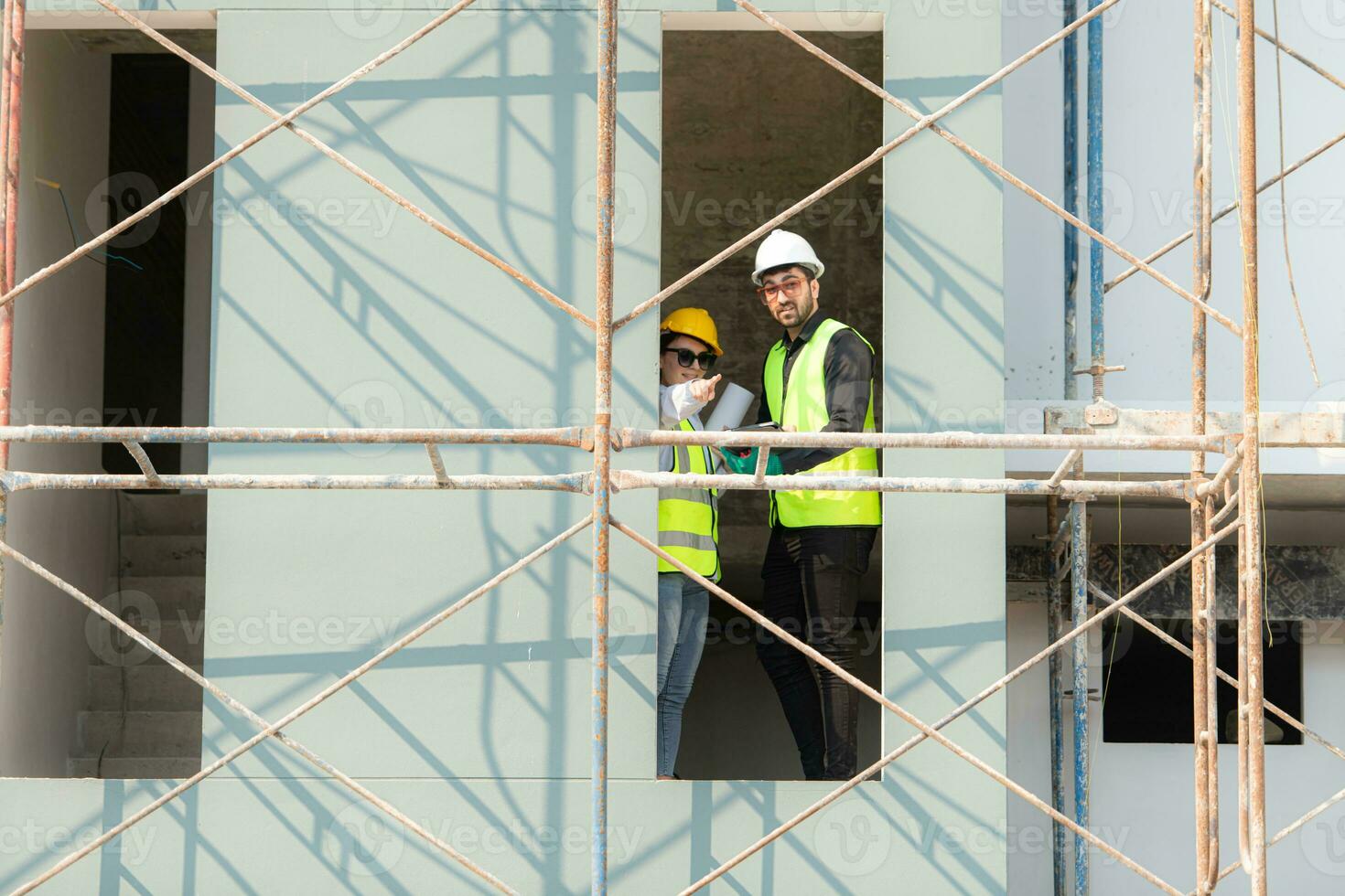 Engineer and architect working on the construction site, double-checking plans and process. photo