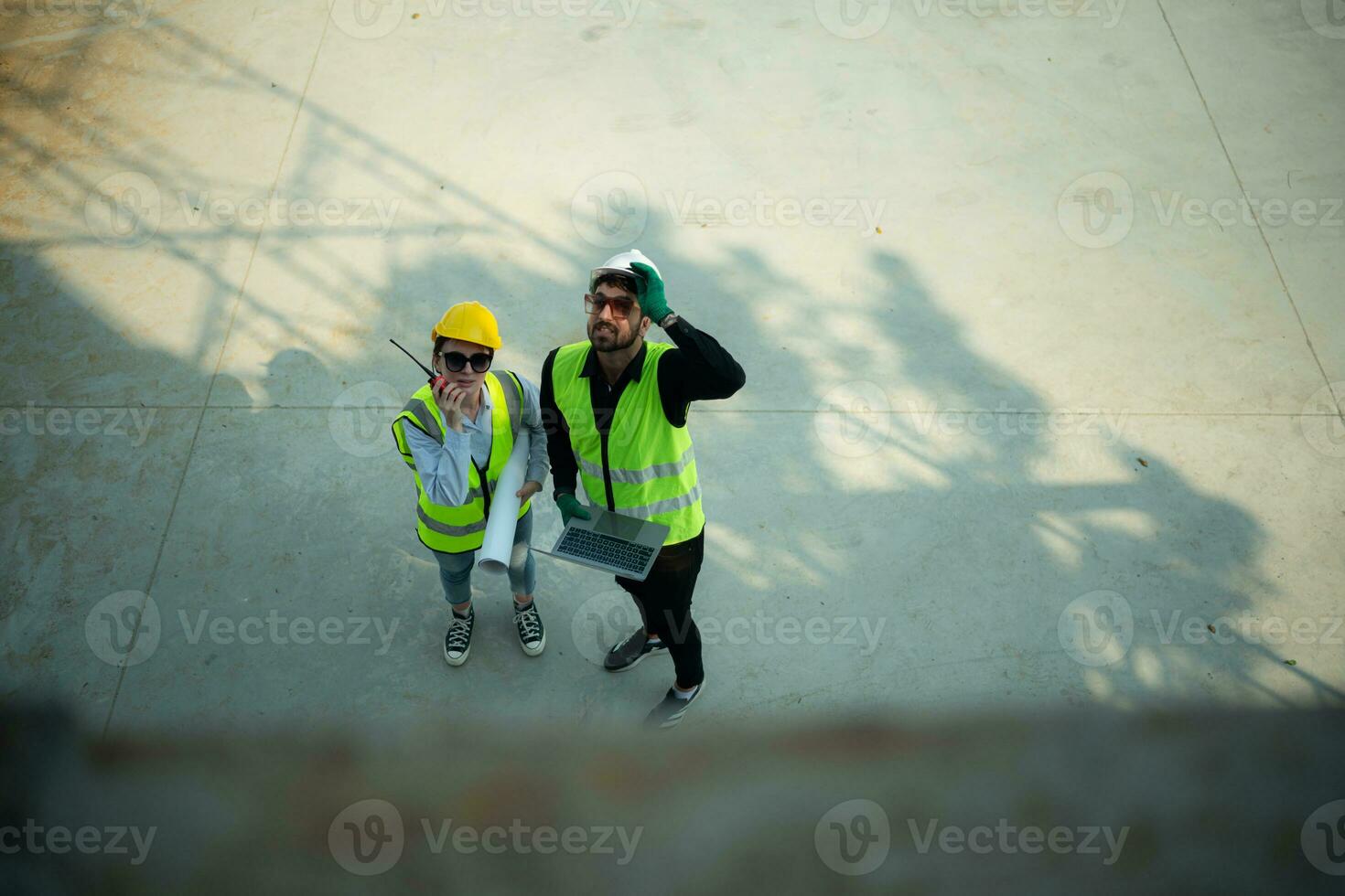 Overhead view on a building site, an engineer and architect are discussing on a laptop. photo