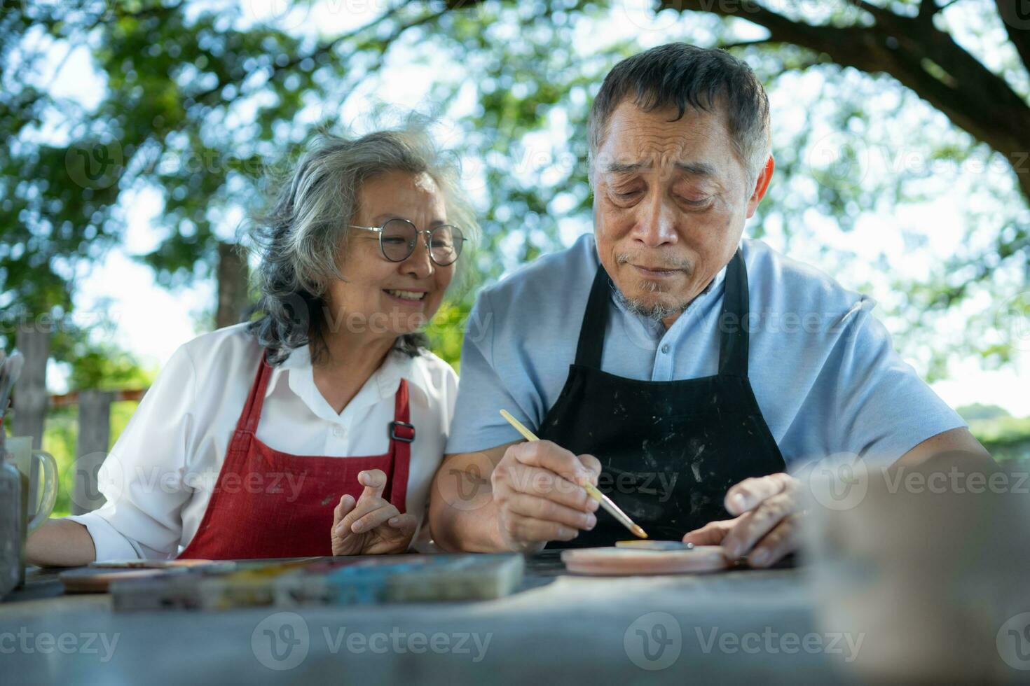 In the pottery workshop, an Asian retired couple is engaged in pottery making and clay painting activities. photo