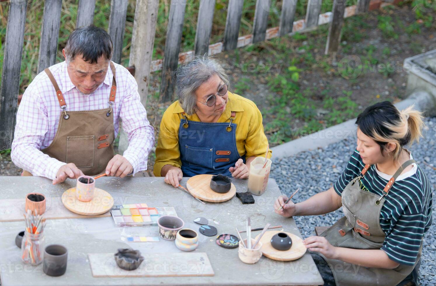 In the pottery workshop, an Asian retired couple is engaged in pottery making and clay painting activities. photo