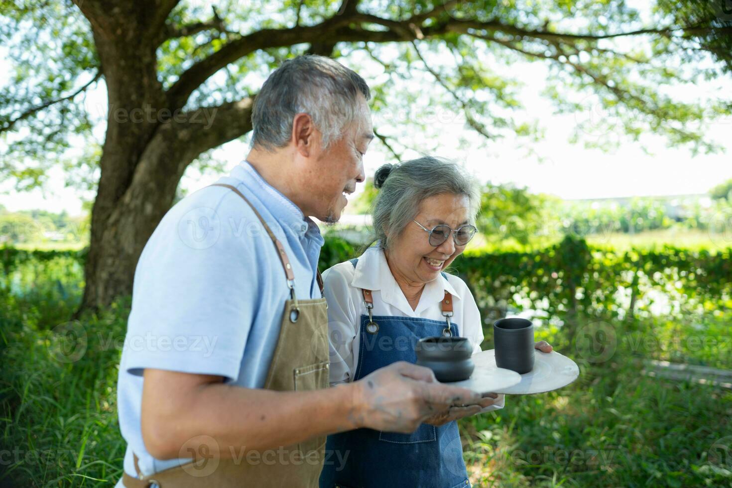 Portrait of a senior Asian couple doing activities together in the pottery workshop. photo