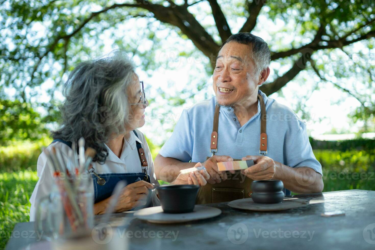 In the pottery workshop, an Asian retired couple is engaged in pottery making and clay painting activities. photo