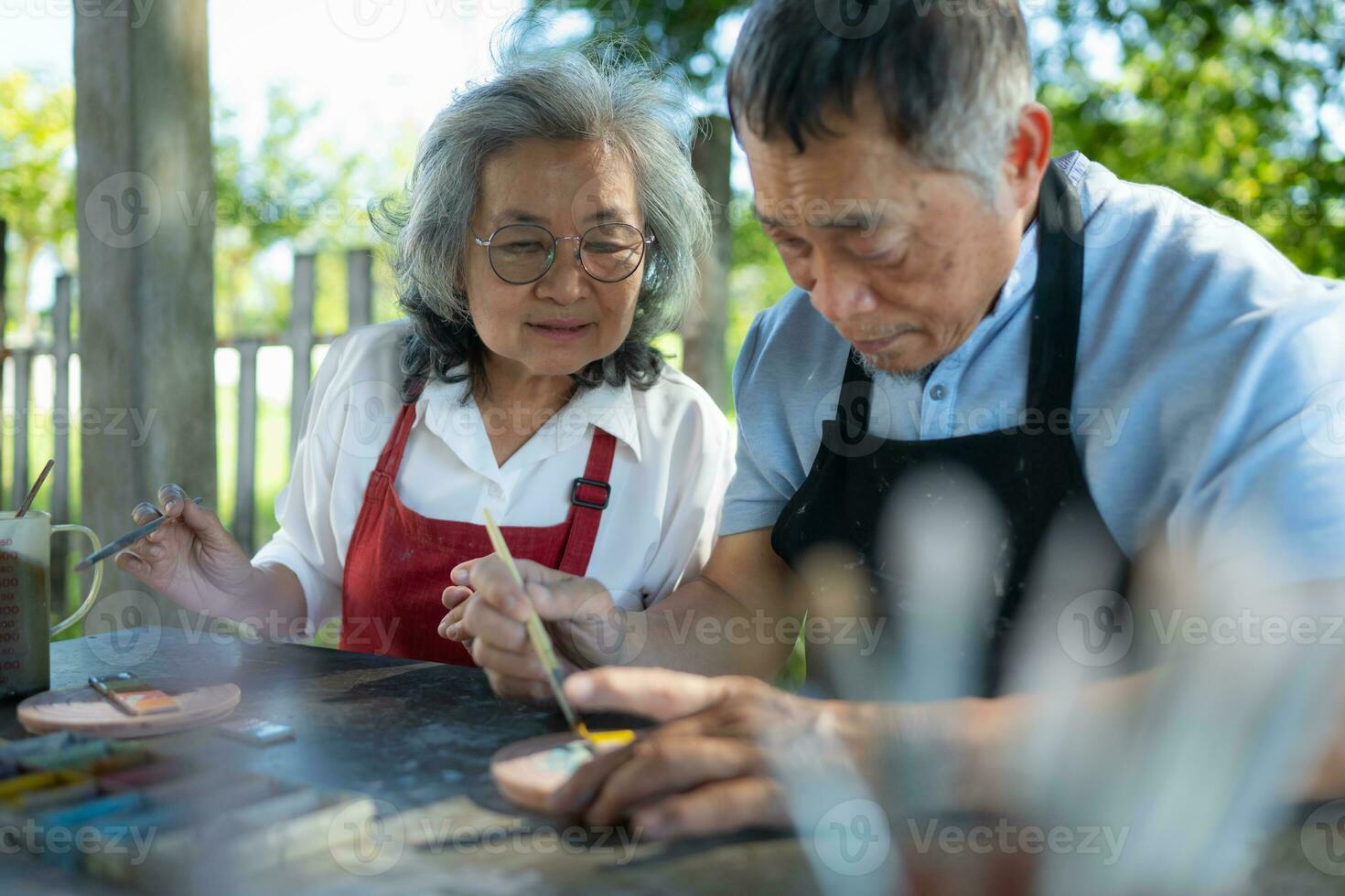 In the pottery workshop, an Asian retired couple is engaged in pottery making and clay painting activities. photo