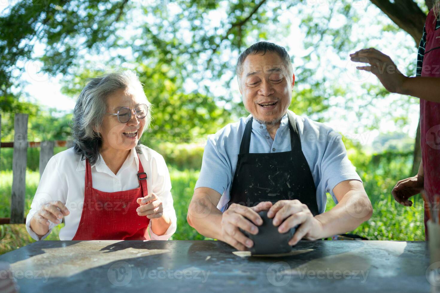 In the pottery workshop, an Asian retired couple is engaged in pottery making and clay painting activities. photo