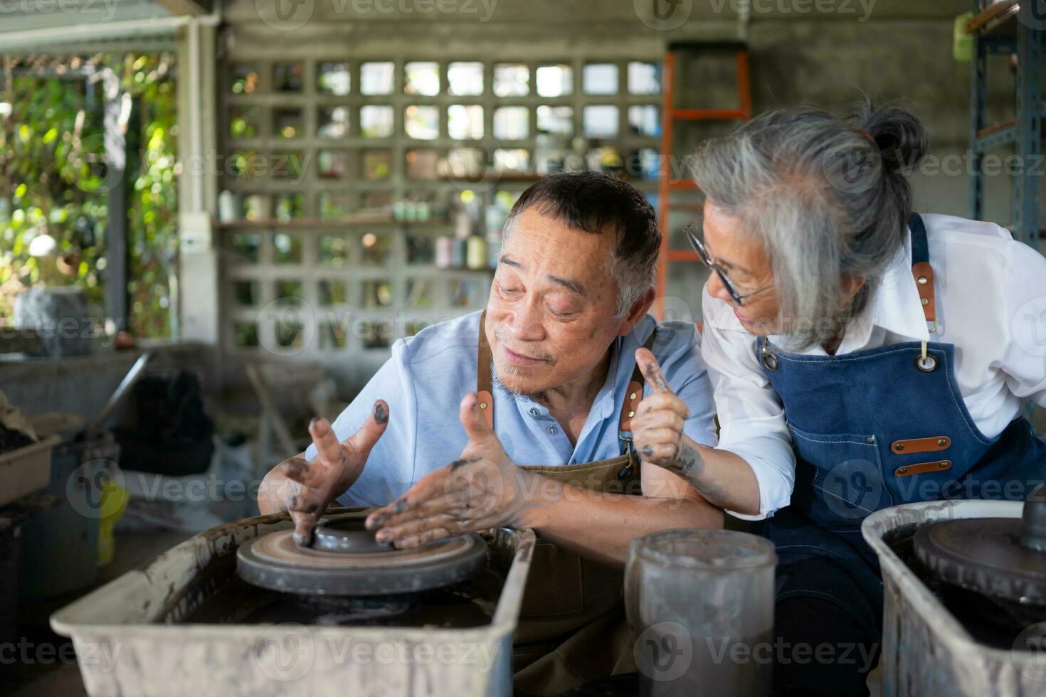 Portrait of a senior Asian couple doing activities together in the pottery workshop. photo