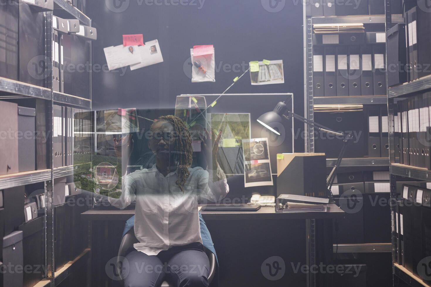 Woman detective looking at evidence in hologram, examining augmented reality image to solve crime in police archive room. Private investigator working with artificial intelligence. photo