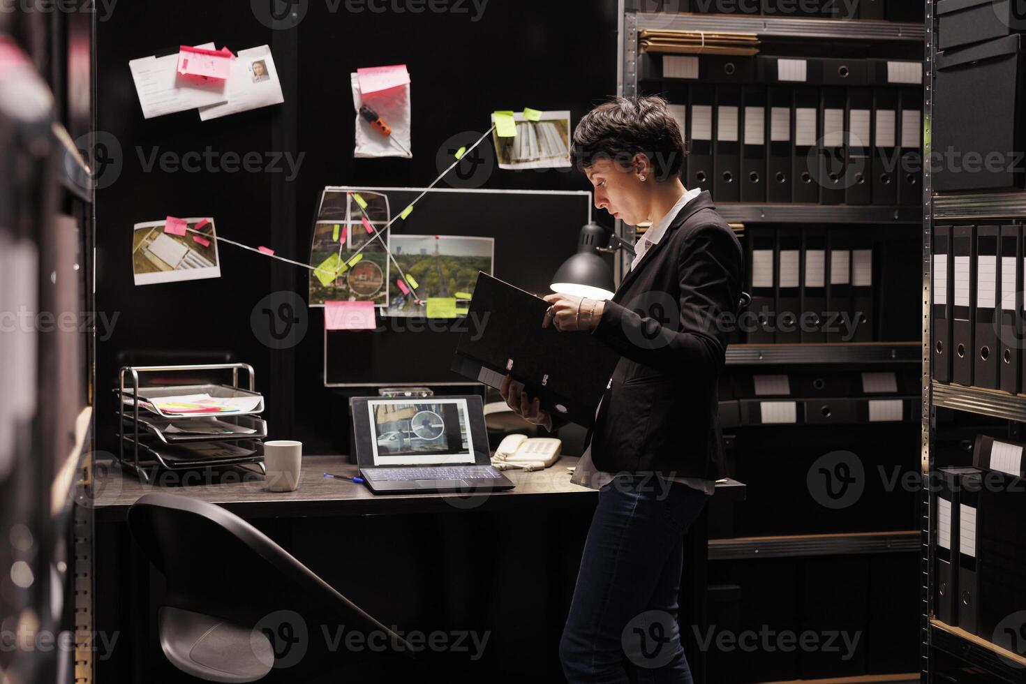 Police officer investigating fraude case analyzing confidential report, working late at night in fbi arhive room. Private detective discovery crime evidence, planning strategy to catch suspect. photo