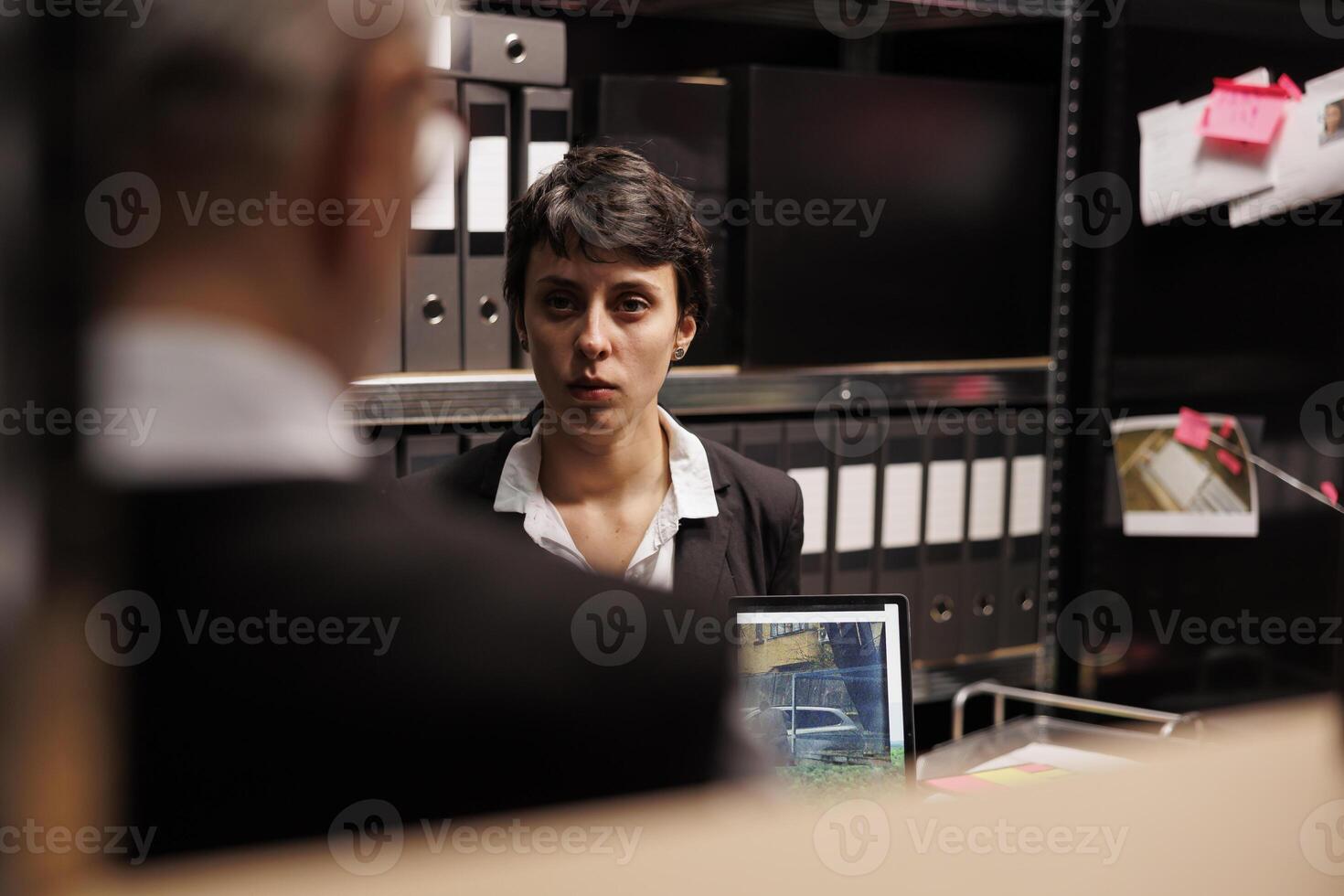 Criminology department workers discussing missing case, analyzing confidential information files. Private investigator discussing suspect report with police officer, working overhours in arhive room photo