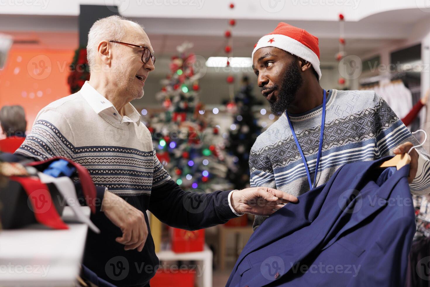 Male employee recommending clothes for senior customer, looking to buy formal outfit for christmas eve dinner. Elderly man asking worker for assistance to choose perfect fit clothing items. photo