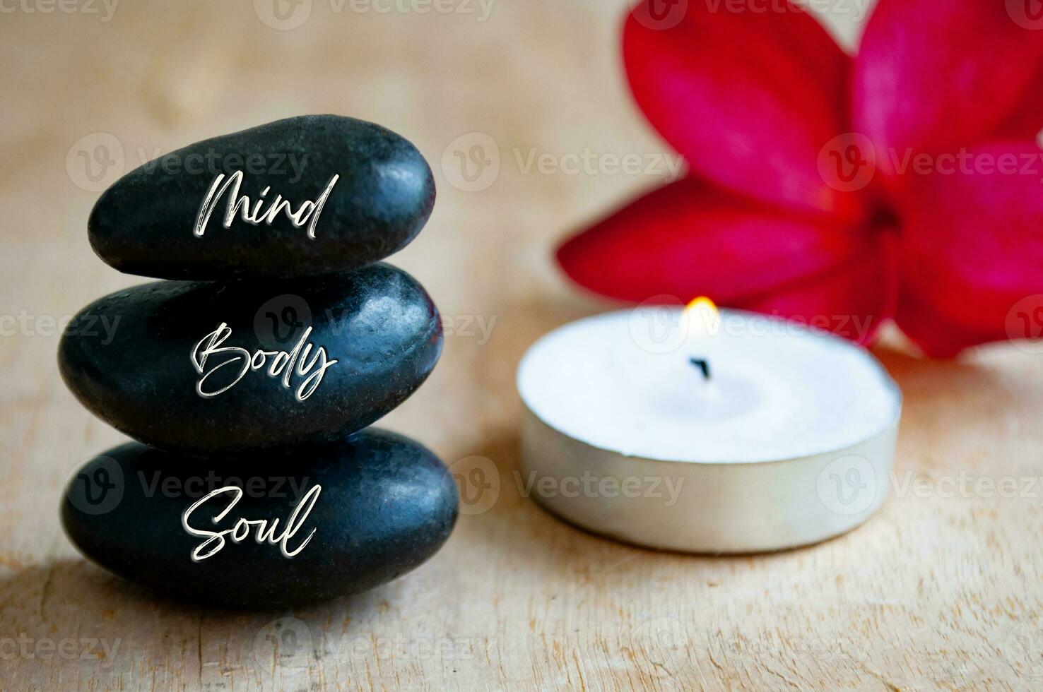 Mind, Body and Soul text engraved on black zen stones with candle. Meditation and spa concept photo