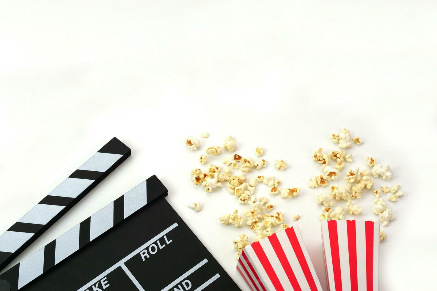 Clapperboard or movie slate black color with popcorn on white background. Cinema industry, video production and film concept. photo