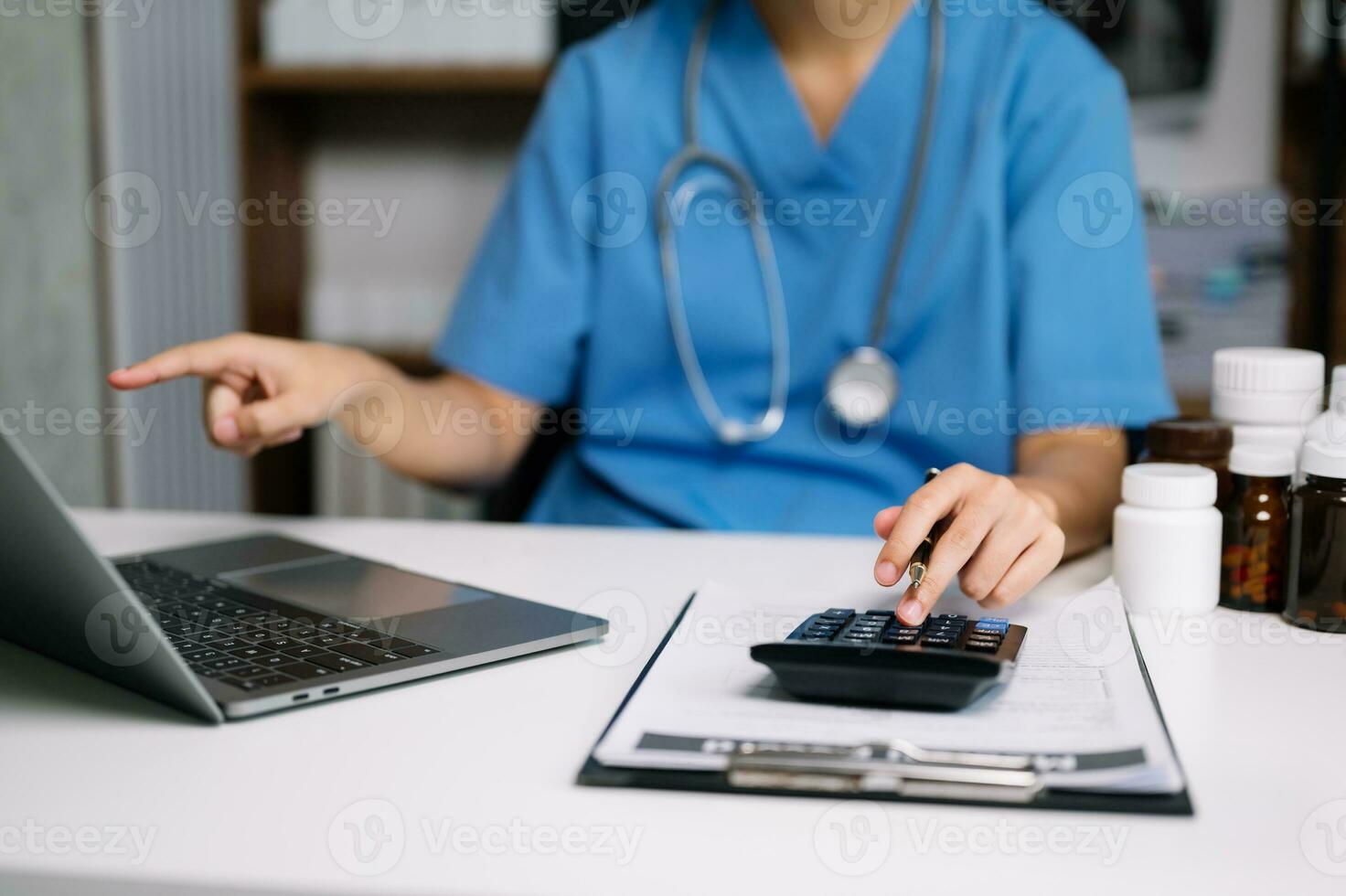 Healthcare costs and fees concept.Hand of smart doctor used a calculator and smartphone, tablet for medical costs at hospital photo