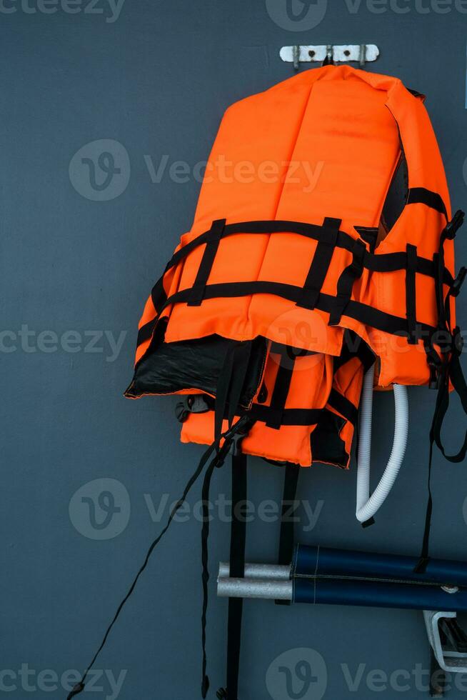 Orange life jackets hanged on wall by swimming pool. photo