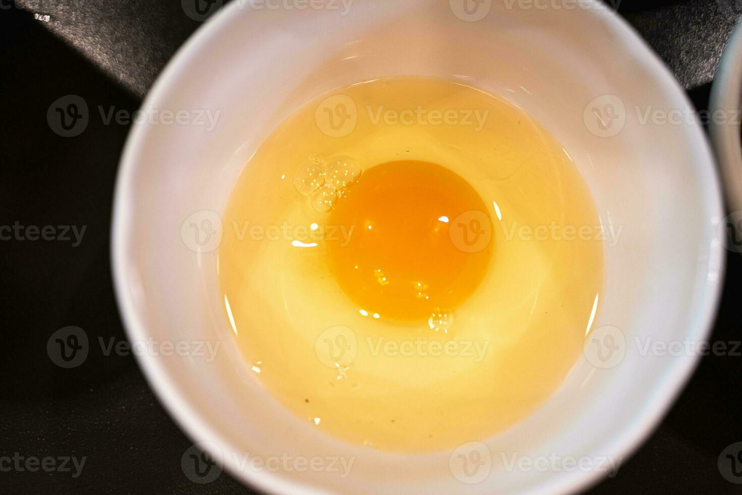 Fresh raw egg in a white bowl photo