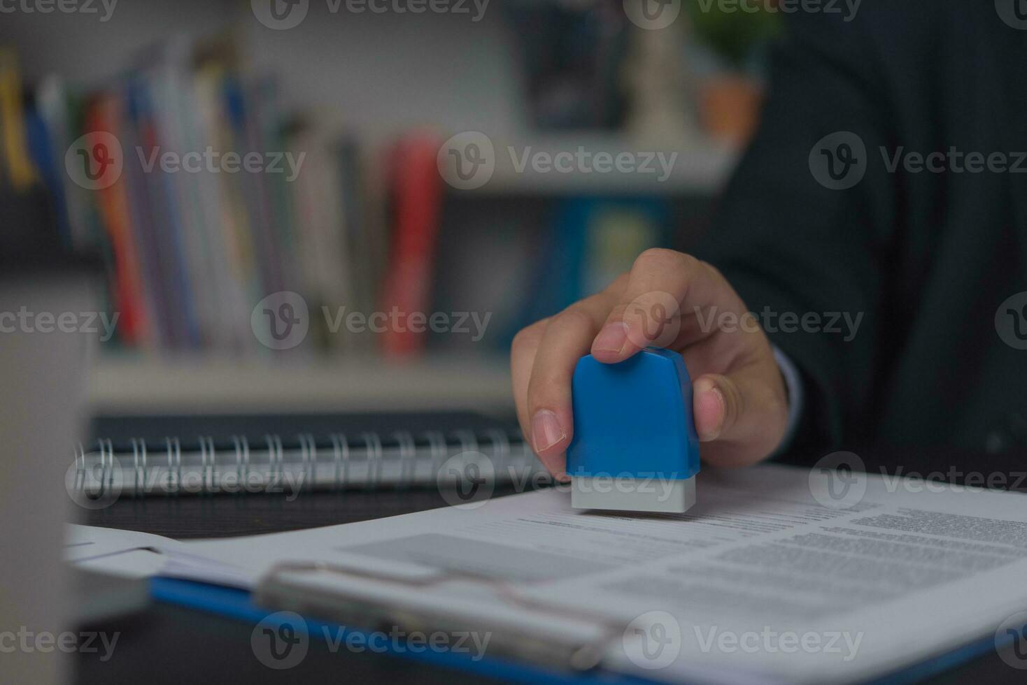 Man stamping approval of work finance banking or investment marketing documents on desk. photo