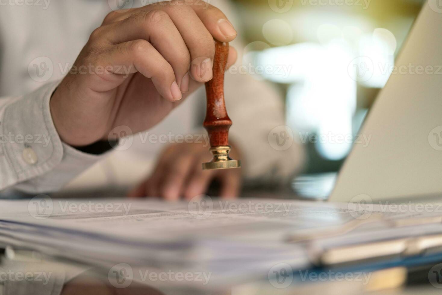 Businessman Stamping Approval on a Document certificate or  Official Law Guarantee contract or visa permit on desk photo