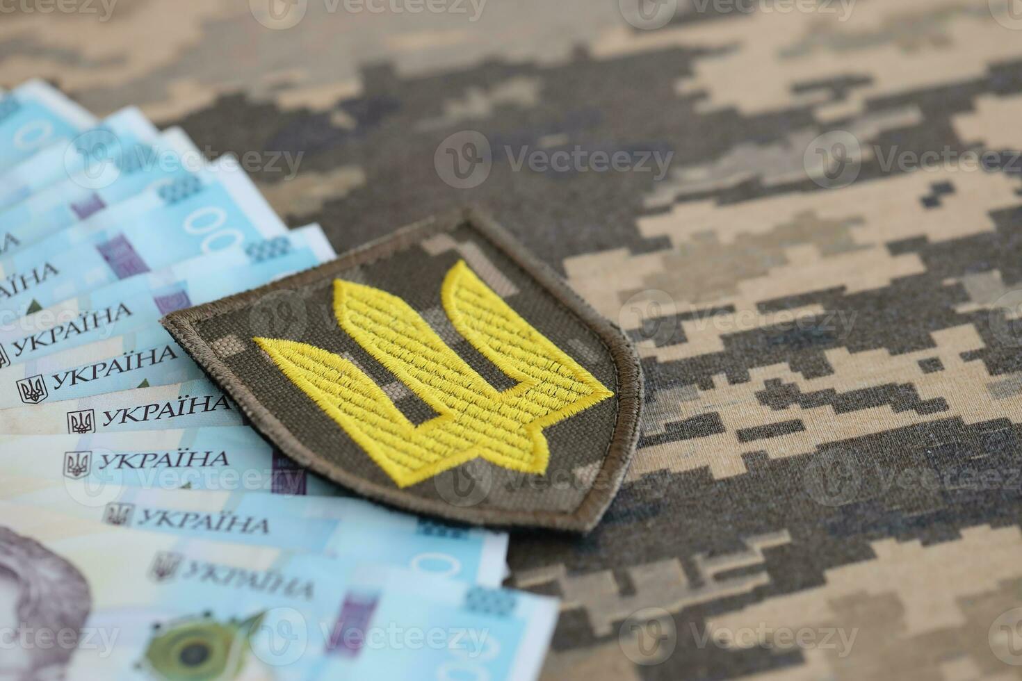 Ukrainian army symbol and bunch of hryvnia bills on military uniform. Payments to soldiers of the Ukrainian army, salaries to the military photo