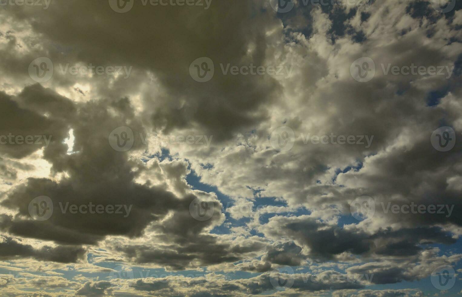 A blue cloudy sky with many small clouds blocking the sun photo