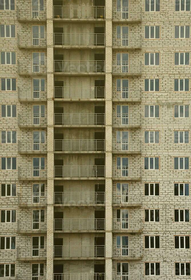 patrón texturizado de una pared de construcción de casas residenciales de piedra blanca rusa con muchas ventanas y balcón en construcción foto