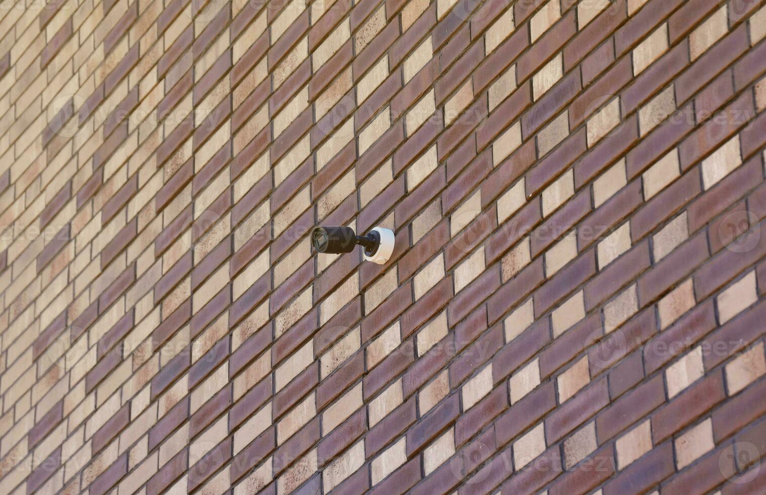 Black wireless CCTV security camera for area surveillance placed on brick wall. Surveillance cameras are modern technology to prevent thieves photo