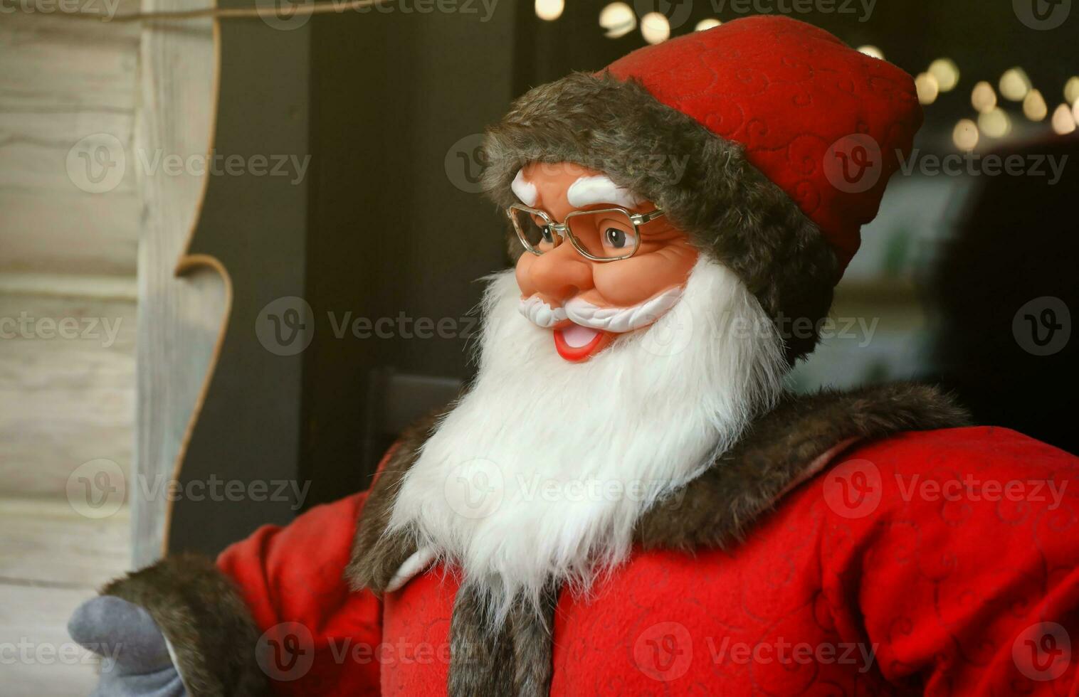Santa claus big plastic figure with classic santa clothes close to wooden house photo