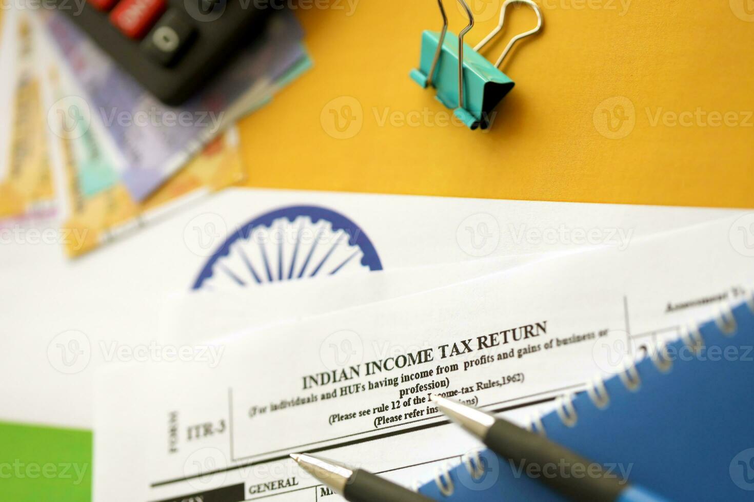 Indian income tax return blank form with pen and indian rupees bills photo