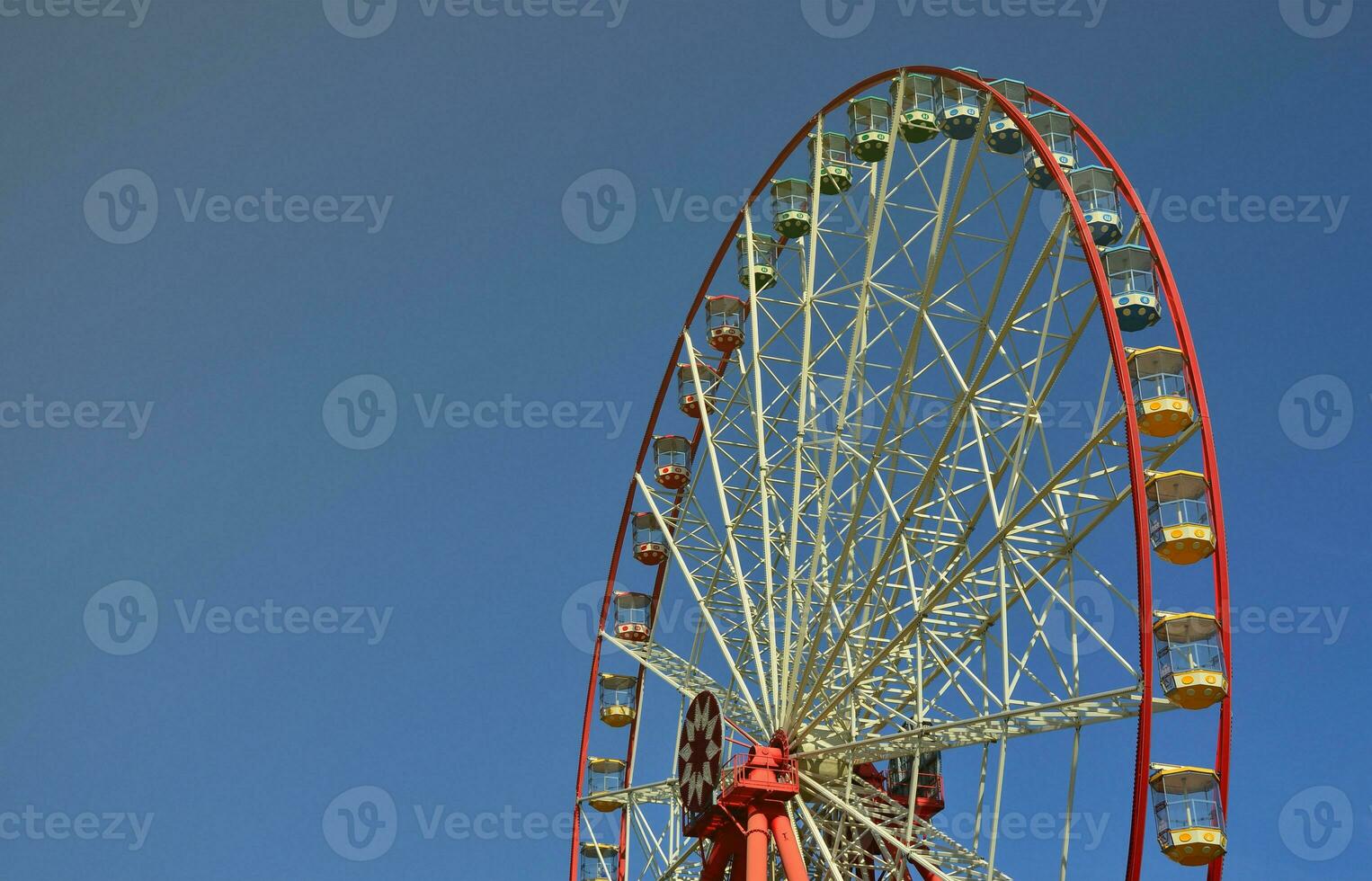 Big and modern multicolour ferris wheel on clean blue sky background photo