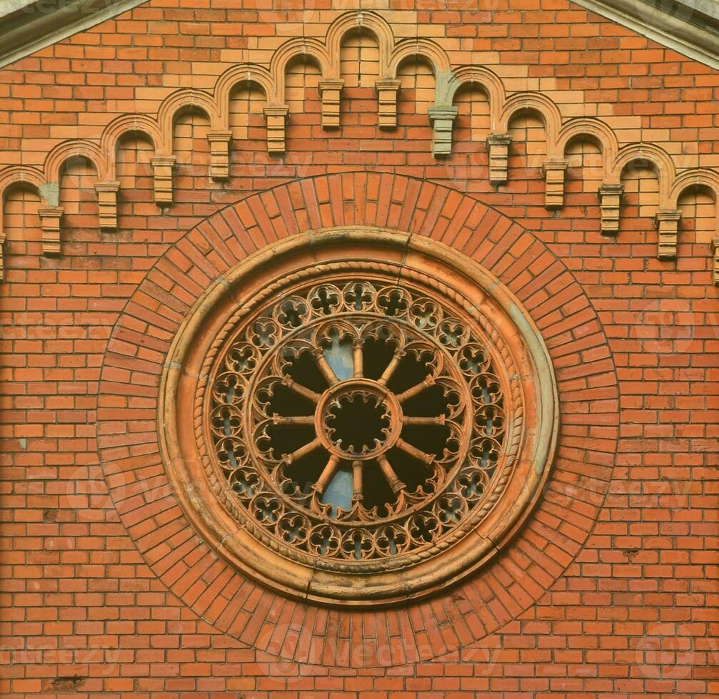 Texture front part of an ancient brick crypt with a round patterned carved window in the cemetery photo