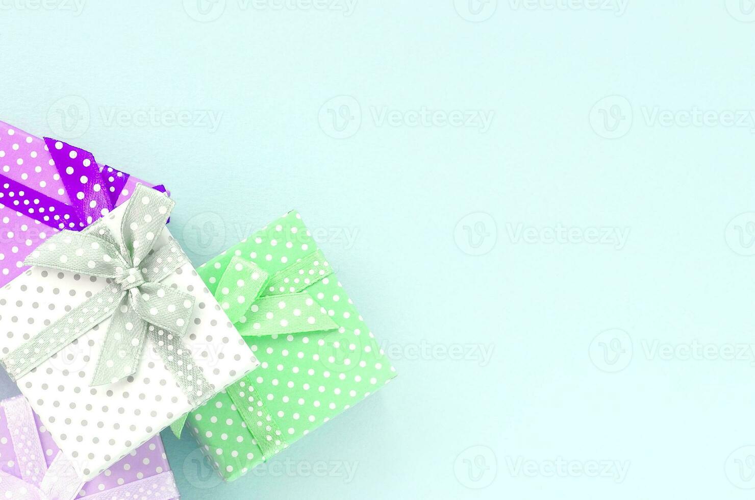 Pile of a small colored gift boxes with ribbons lies on a violet background. Minimalism flat lay top view photo