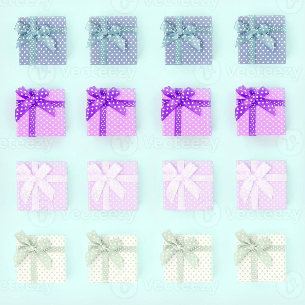 Piles of a small colored gift boxes with ribbons lies on a violet background. Minimalism flat lay top view pattern photo