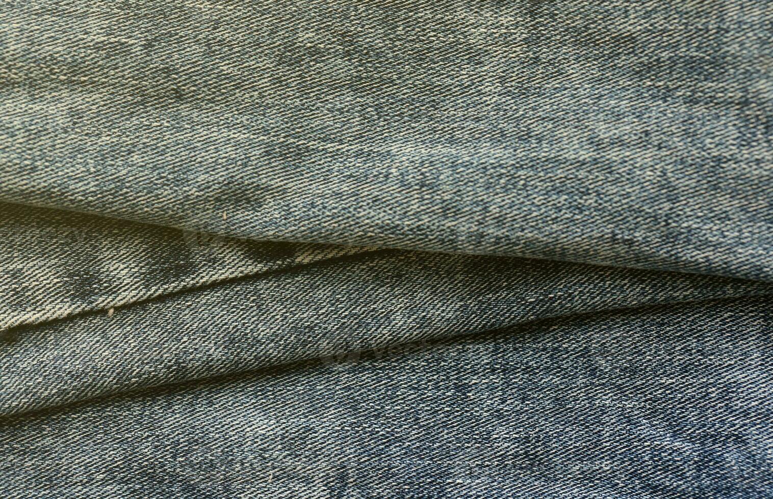 Detailed abstract texture of dark blue denim cloth. Background image of old used denim trousers fabric photo