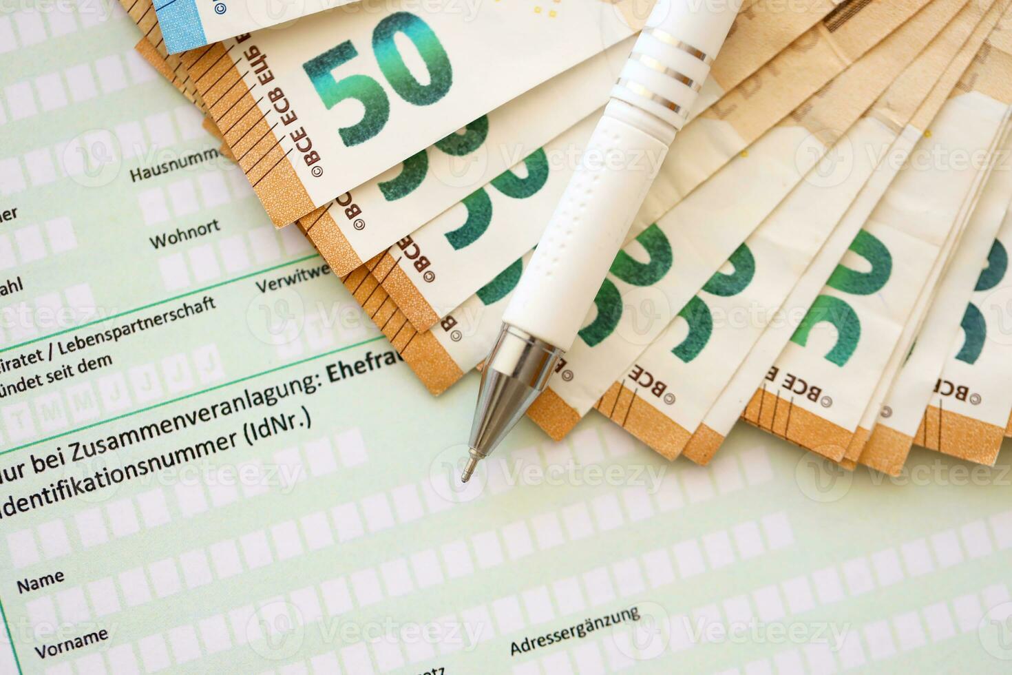 Filling german tax form process with pen and euro money bills close up. Tax paying period photo