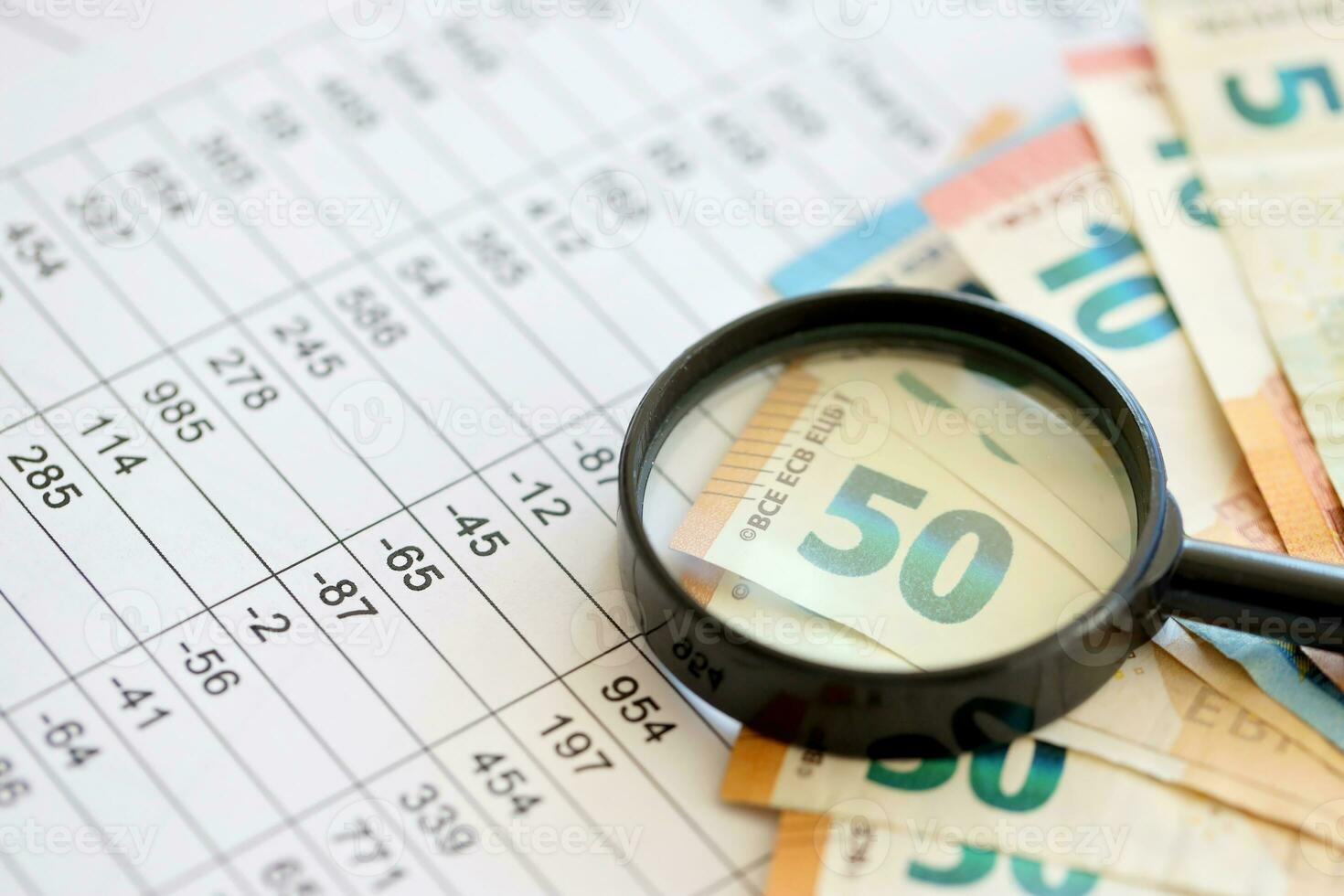 Business and savings concept with many euro money bills and magnifying glass photo