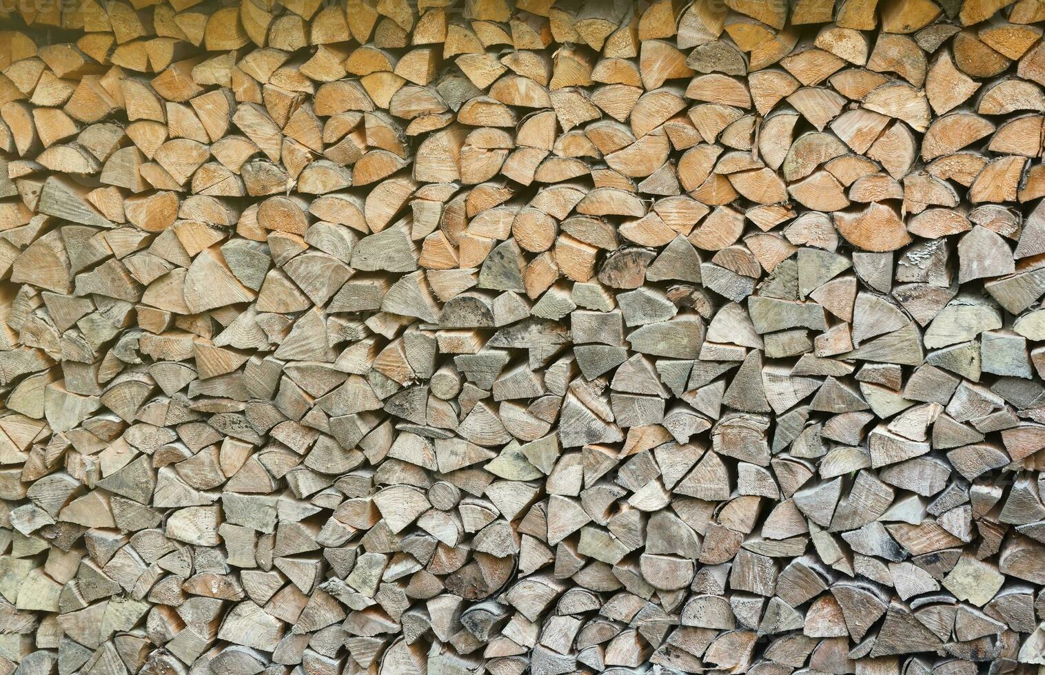 Firewood stacked near the wooden wall of old hut. Many chopped logs of firewood photo