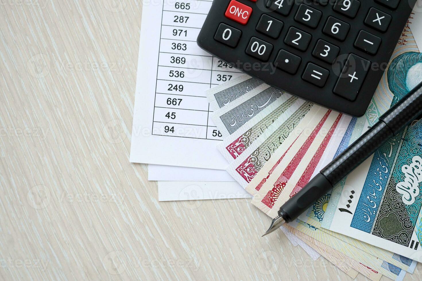 Iranian business calculations on table with iranian money and pen photo