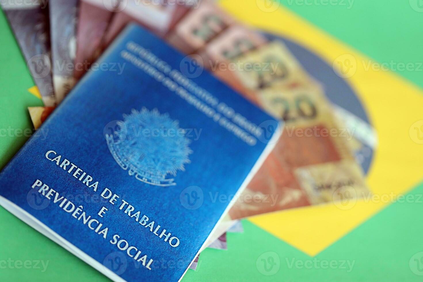 Brazilian work card and social security blue book and reais money bills on flag of Federative Republic of Brazil photo
