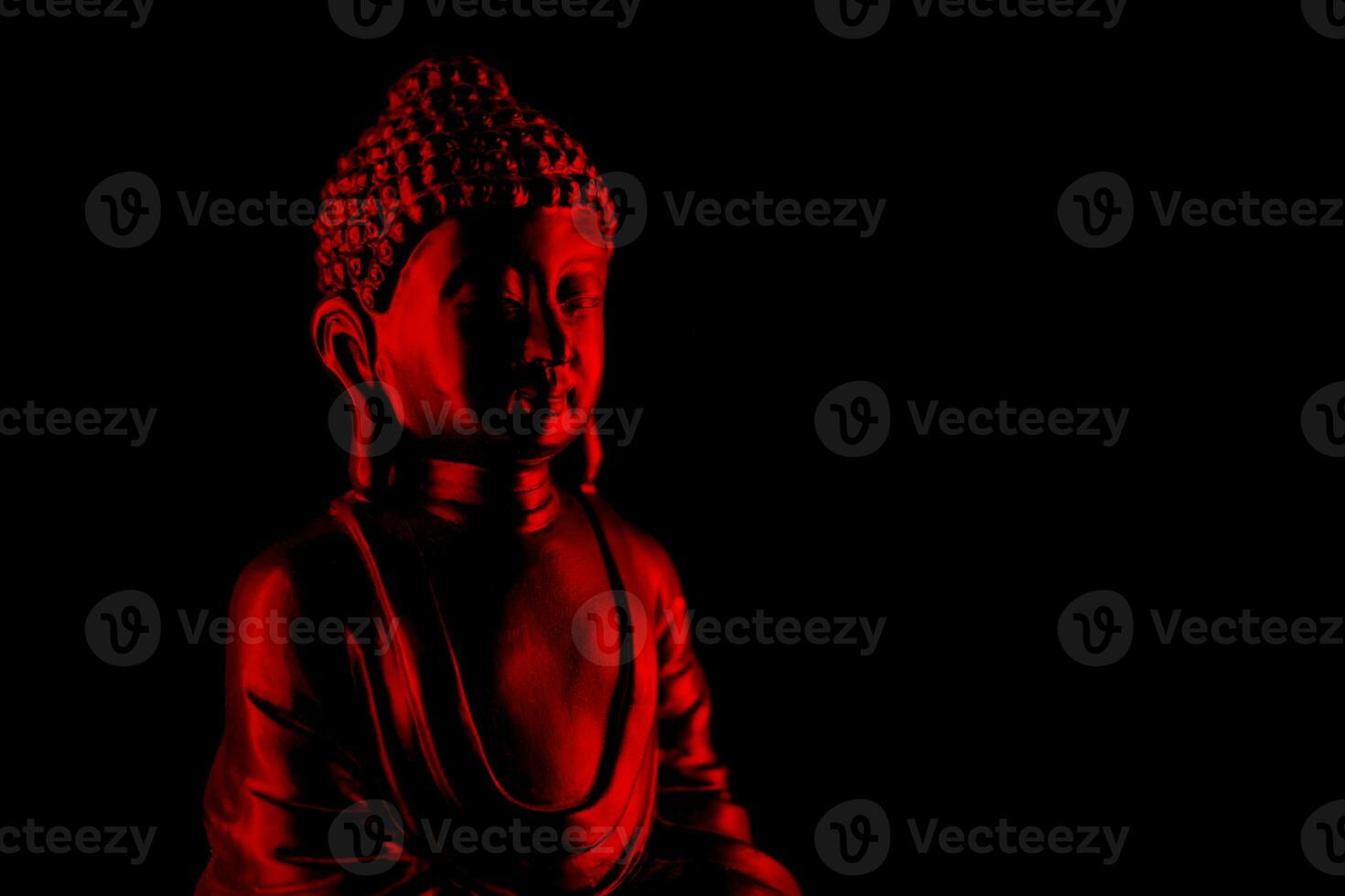 Buddha Purnima and Vesak day concept, Red Buddha statue with low key light against deep black background photo