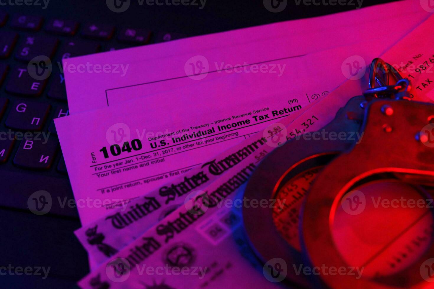 US Tax refund check and handcuffs on computer keyboard close up photo