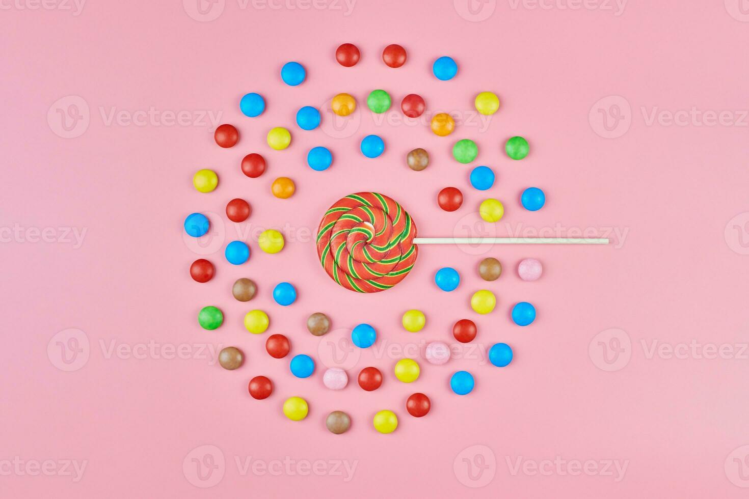 piruleta dulce y caramelo sobre fondo rosa foto