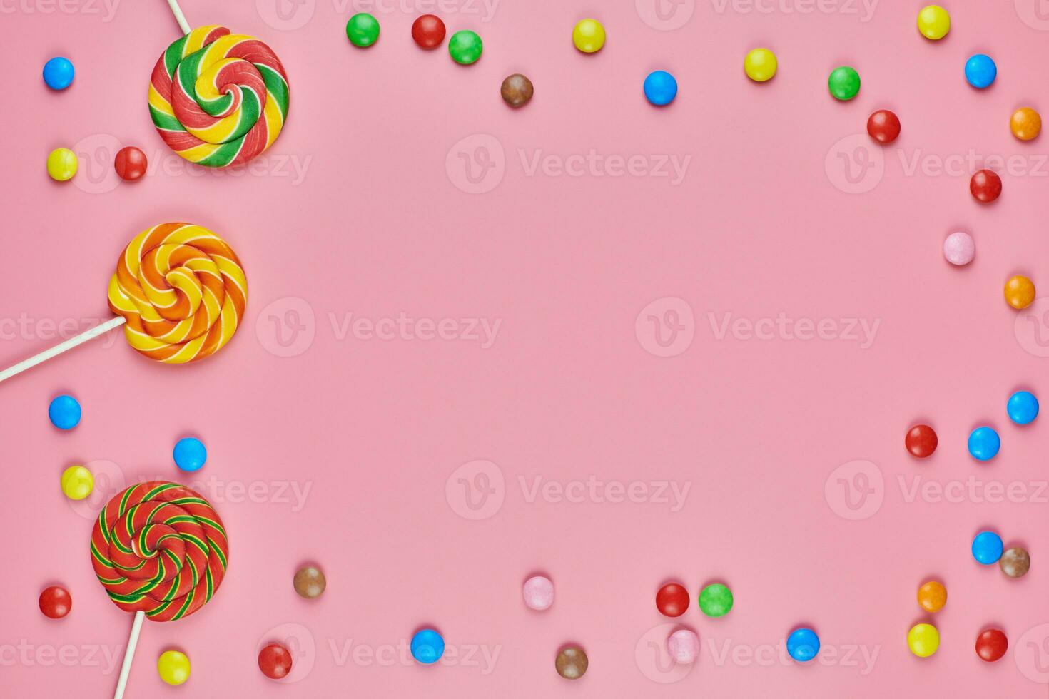 Sweet candy copy space frame with lollipops on pink background photo