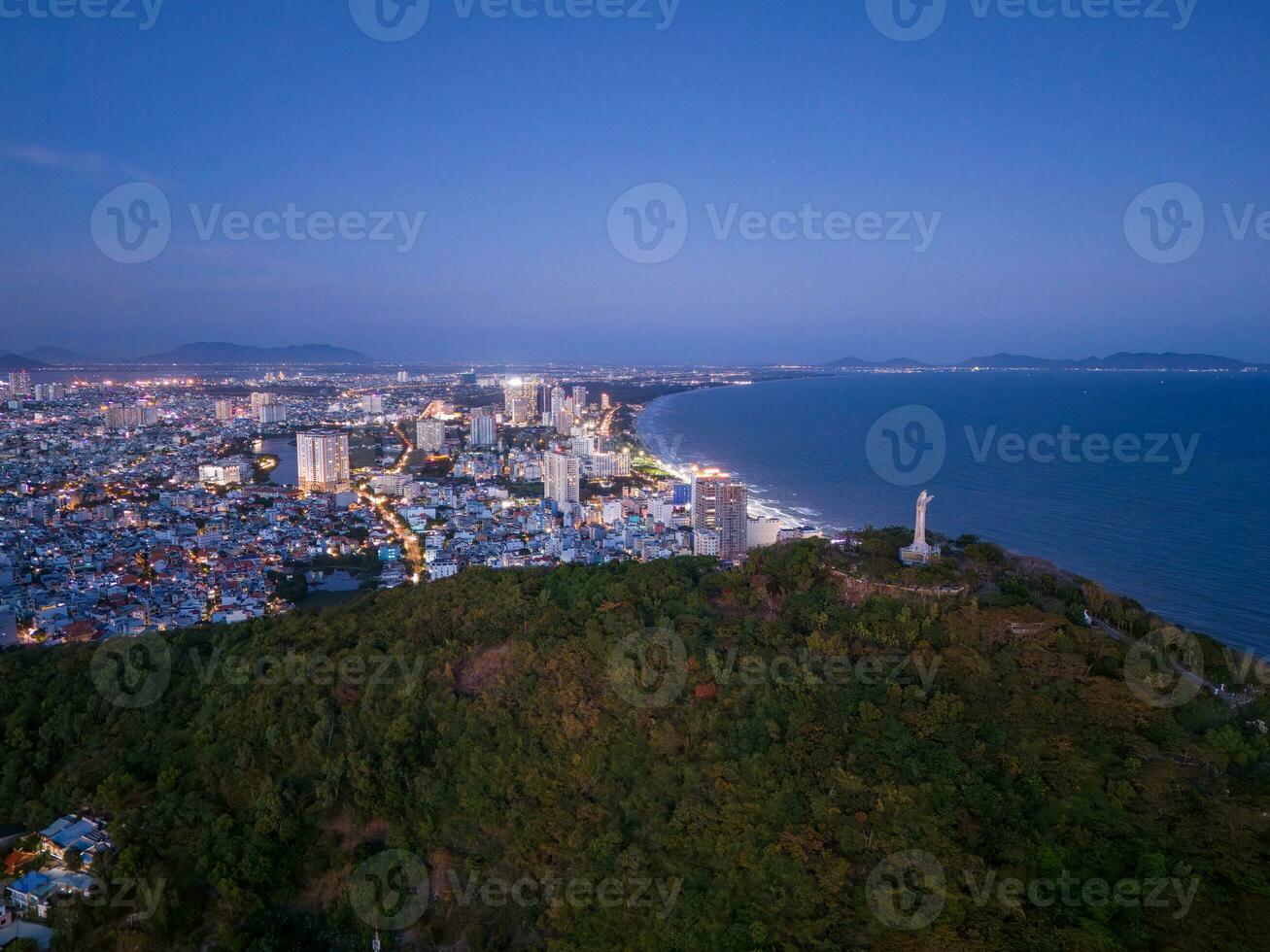 Panoramic coastal Vung Tau view from above, with waves, coastline, streets, coconut trees, Mount Nho in Vietnam behind the statue of Christ the King photo