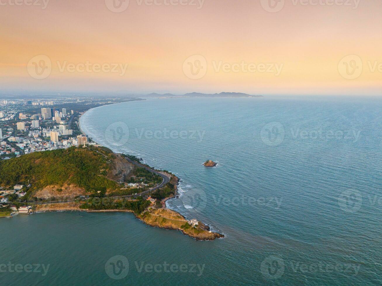 Panoramic coastal Vung Tau view from above, with waves, coastline, streets, coconut trees, Mount Nho in Vietnam behind the statue of Christ the King photo