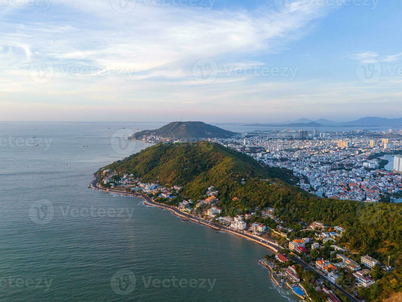 Panoramic coastal Vung Tau view from above, with waves, coastline, streets, coconut trees, Mount Nho in Vietnam behind the statue of Christ the King photo